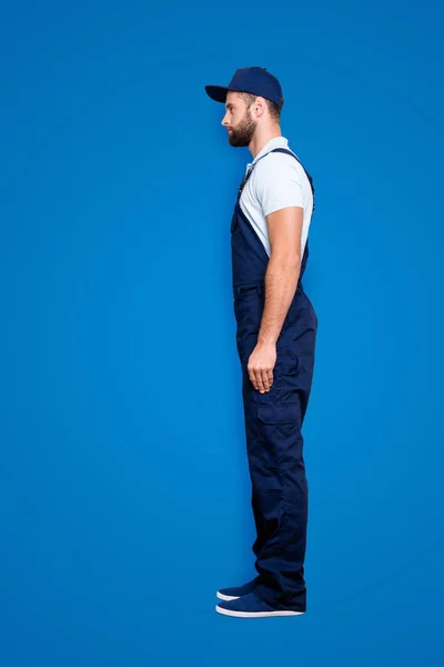 Full size body profile portrait, snap of attractive, confident deliver in blue uniform with stubble, isolated on grey background.
