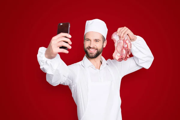 魅力的なハンサムな肉屋の肖像画とともに頑固な撮影自撮りスマートフォンのフロントカメラ 手に新鮮な肉を保持 ビデオ通話を持つブロガー 灰色の背景に隔離 — ストック写真