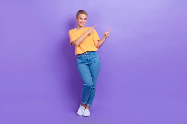 フルサイズ写真の満足かわいい女の子の服のスニーカーデニムパンツ示す空のスペース孤立した紫の色の背景 — ストック写真