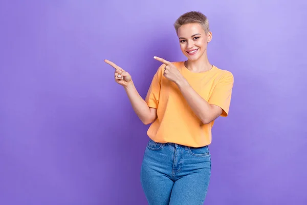 年轻的促销人员积极女士穿着休闲装 指指点点 空空荡荡的新系列在紫色背景下被分离出来 — 图库照片