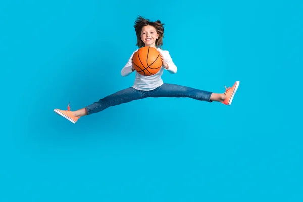 身穿白色长袖长裤 背带蓝色背景的篮球跳跃的可爱精力充沛的女孩的全长照片 — 图库照片