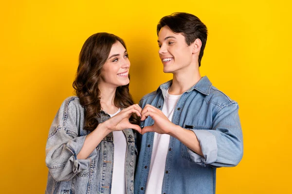Photo of dreamy sweet couple dressed denim showing arms heart isolated yellow color background.