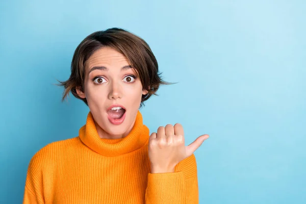 Photo portrait of lovely young lady astonished shocked point empty space dressed stylish orange clothes isolated on blue color background.