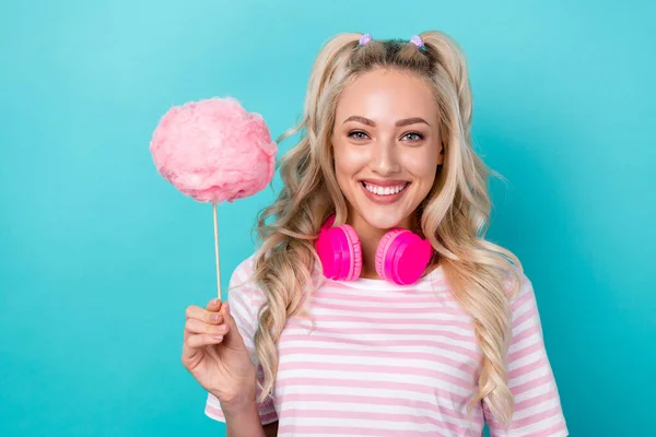 Photo of cheerful funky girl hold puffy cotton candy stick headphones hang neck isolated on teal color background.