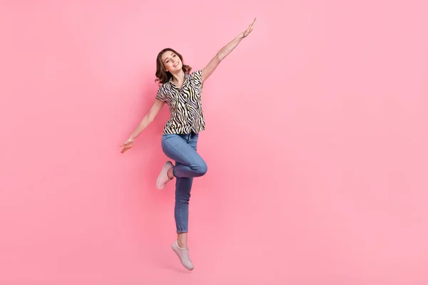 欢快可爱女孩跳跃的全长肖像举起双臂空荡荡的空间广告用粉色背景隔开 — 图库照片