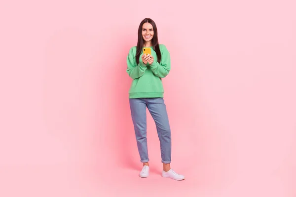 正の女性中毒ユーザーの完全な長さの写真は ピンクの色の背景に隔離された新しい品質のデバイスを促進緑のトレンディーな服を着用 — ストック写真