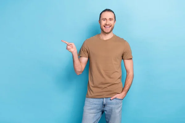 Photo of friendly satisfied person toothy smile direct finger empty space news isolated on blue color background.