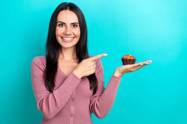 Photo of nice cheerful lady toothy smile direct finger arm hold muffin dessert isolated on teal color background.