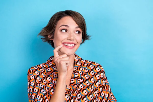 Photo of positive minded lady beaming smile finger touch lip look empty space isolated on blue color background.
