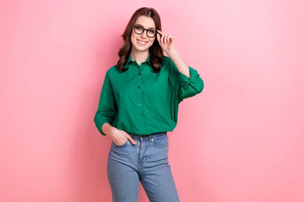 良い気分の肖像美しいですスマート女の子巻きヘアスタイルは ピンクの背景に隔離されたポケットに触れる眼鏡で緑のシャツ腕を身に着けている — ストック写真