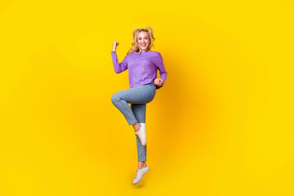 魅力的な若い女性のジャンプのフルボディ写真は拳を上げるお祝い服スタイリッシュなバイオレット衣装黄色の背景に隔離された — ストック写真