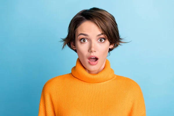Photo portrait of attractive young woman astonished hear shocking news dressed stylish orange clothes isolated on blue color background.