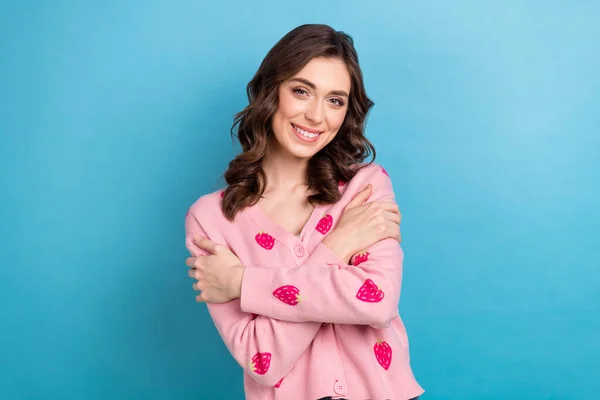 Photo of pretty sweet woman wear pink cardigan smiling embracing herself isolated blue color background.
