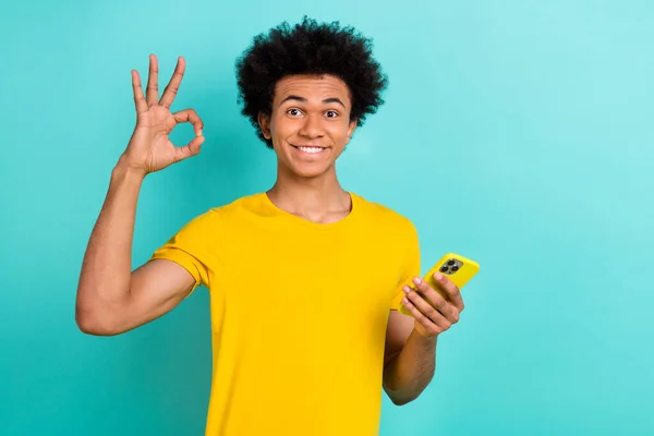 乐观的心满意足的男人穿着黄色T恤衫的画像 画面上挂着一把带着活力四射色彩背景的智能手机 — 图库照片