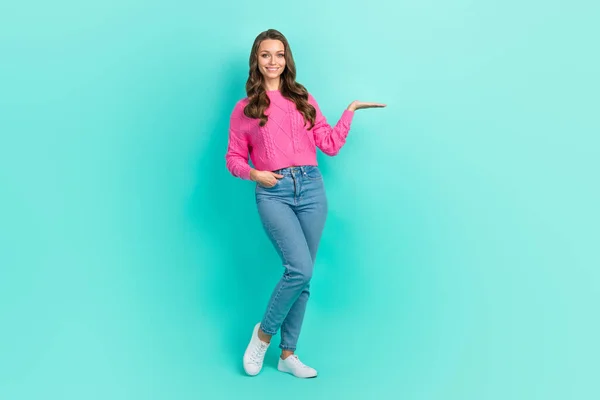 フル長さ写真のかなり光沢のある女の子着用ピンクセーター保持アーム空のスペース隔離されたターコイズ色の背景 — ストック写真