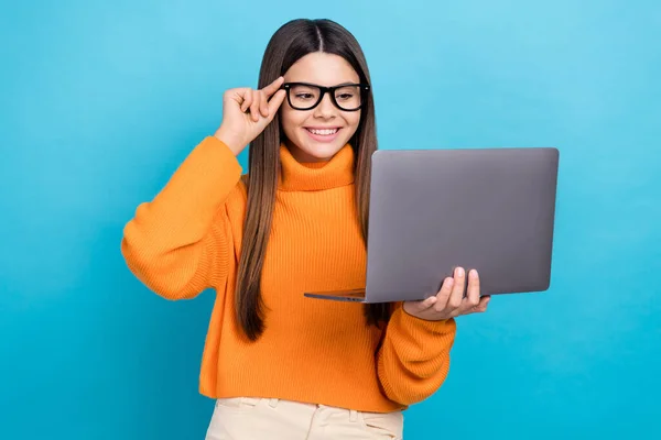 滑稽聪明漂亮女孩长发的照片 戴着针织高领隐形眼镜 望着蓝色背景的笔记本电脑 — 图库照片