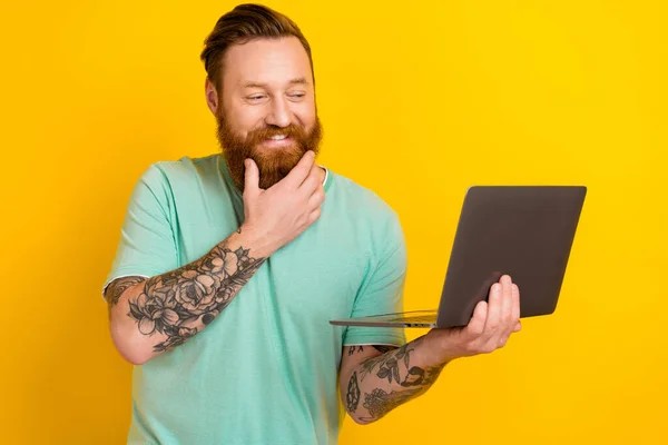 Photo of positive nice man hand touch chin beard use wireless netbook isolated on yellow color background.