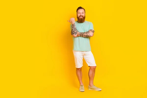 Full body photo of young man red hair long beard hipster outfit tattooed hands direct finger mockup summer sale isolated on yellow color background.