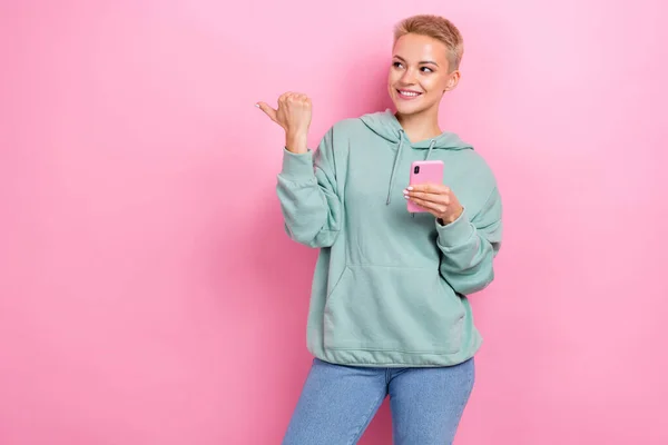 若いプロモーションの写真魅力的なヒップスターブロンド短い髪の女の子のブロガーは ピンクの色の背景に隔離されたスマートフォンの直接指の外観の新しいアプリを保持 — ストック写真