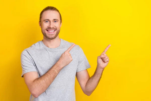 甜美快乐的男人穿着灰色T恤衫指着两个手指凸出的空间孤立的黄色背景的照片 — 图库照片