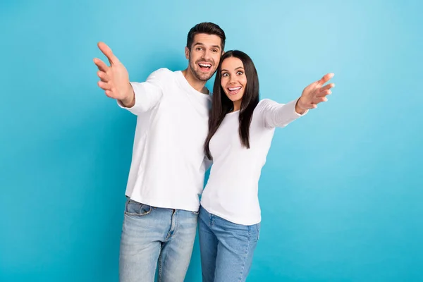 Photo of two impressed cheerful funny positive couple people wear white shirts cuddling glad to see you isolated on blue color background.