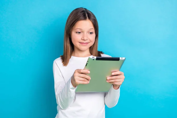 聪明的女学生穿着直发白衬衫的照片看着平板电脑在蓝色背景下独立做作业 — 图库照片