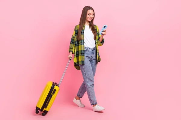 迷人人的全长肖像用智能电话托着手提箱 在粉色背景下独立行走 — 图库照片