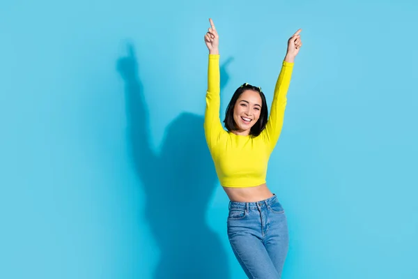 Photo of excited carefree gorgeous person point fingers dancing empty space isolated on blue color background.