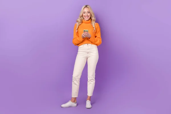 明るいです美しいです女性ホールドのフルボディ写真使用スマートフォンチャット孤立した上に紫色の背景 — ストック写真