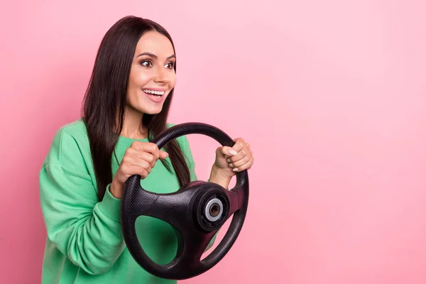 年轻女司机黑发女司机手握方向盘身穿绿色衬衫兴奋地快速驾驶红色背景的汽车的合影 — 图库照片