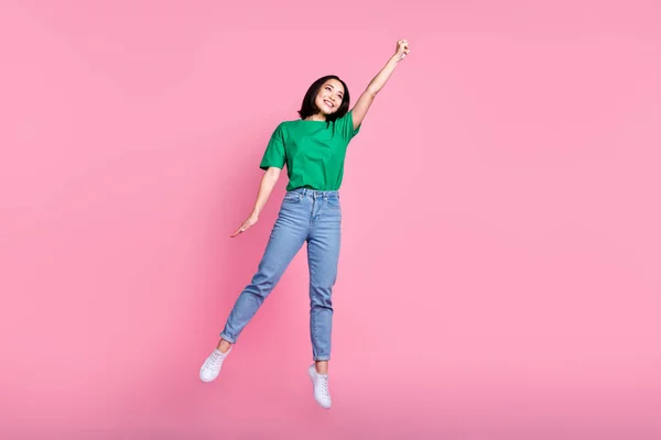Full size photo of cheerful adorable woman wear oversize t-shirt jeans flying jumping having fun isolated on pink color background.