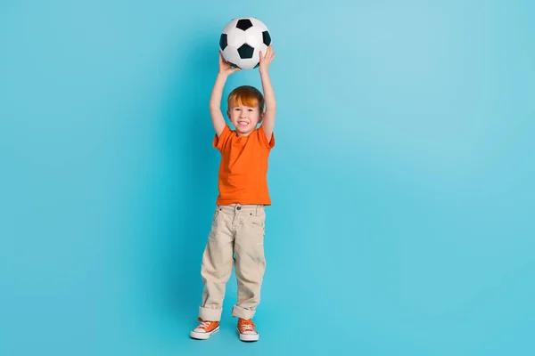 Full length photo of positive cheerful boy fan hold ball win final league fifa match empty space isolated on cyan color background.