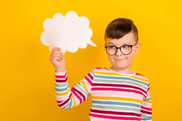 Photo of smart clever boy wear striped trendy clothes hold cloud card tell comment look empty space isolated on yellow color background.