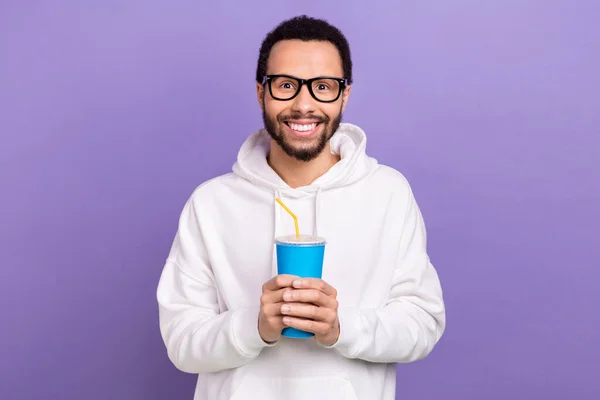 Portrait of young smile man wear pullover new glasses hold plastic cup drinking coke fresh lemonade isolated on purple color background.