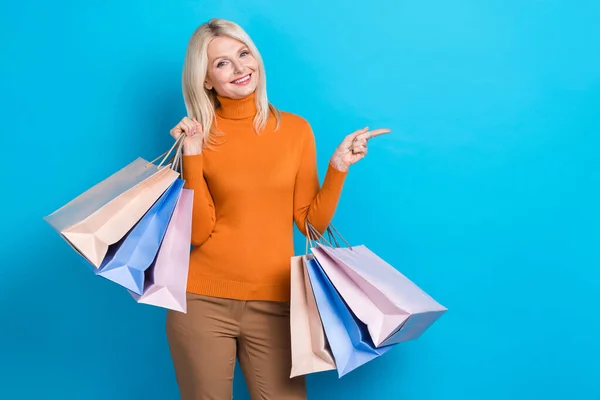 Portrait of gorgeous lovely lady wear trendy clothes hold packages demonstrate empty space mall center isolated on blue color background.