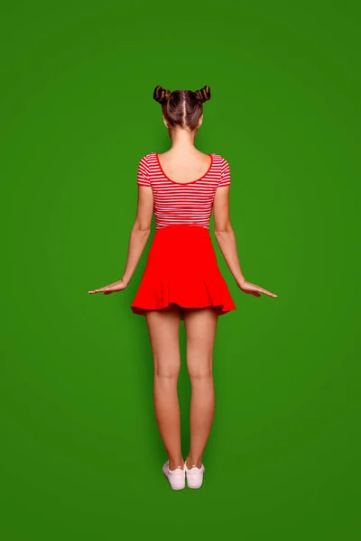 明るい赤の背景にカメラに背を向けて立っている少女の肖像画をフルサイズ完全レー — ストック写真