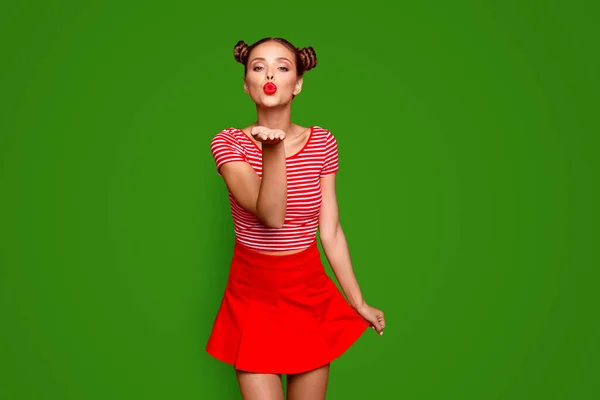 可愛いです女の子送信Aキスのためにあなた上の素晴らしいですメークアップ身に着けているストライプTシャツと赤スカート絶縁上の明るい背景と送信空気キスからオープンパーム — ストック写真