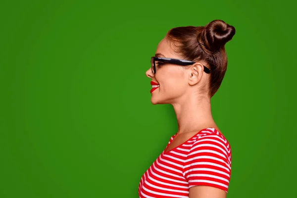 Half-faced side profile view portrait of happy confident woman dressed in striped shirt and spectacles isolated on red background with copy space for text.