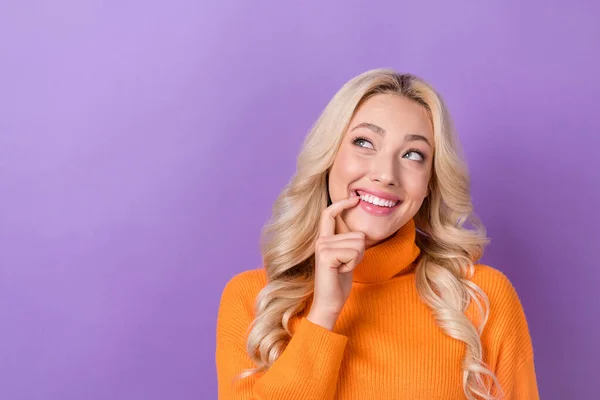 スタイリッシュな髪型と楽観的なセクシーな女の子の写真オレンジのセーターは 紫色の色の背景に隔離された空のスペース指の歯を見えます — ストック写真