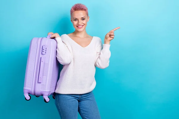Photo of optimistic attractive pretty woman tourist direct finger mockup worldwide airport hold suitcase baggage isolated on cyan color background.