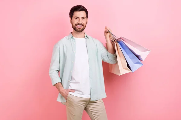 写真のポートレートの素敵な若い男性ホールドショッピングバッグパッケージ黒金曜日着用トレンディーな青の服隔離ピンク色の背景 — ストック写真