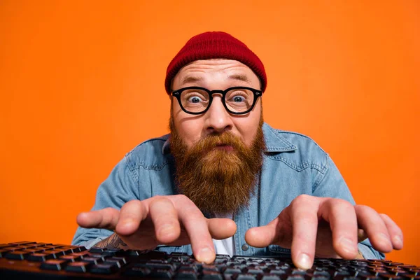 Photo of geek nerd guy dressed denim jacket eyeglasses communicating modern gadget isolated orange color background.