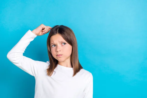 Photo of minded intelligent girl long hairstyle wear white long sleeve finger on head look empty space isolated on blue color background.