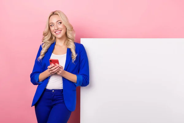 stock image Photo of dreamy sweet woman dressed blue blazer texting device looking placard empty space isolated pink color background.