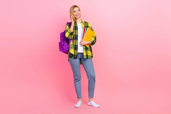 フルボディ写真の美しい若い女性トーク電話帳学生服スタイリッシュなチェッカー黄色の衣装に隔離されたピンク色の背景 — ストック写真