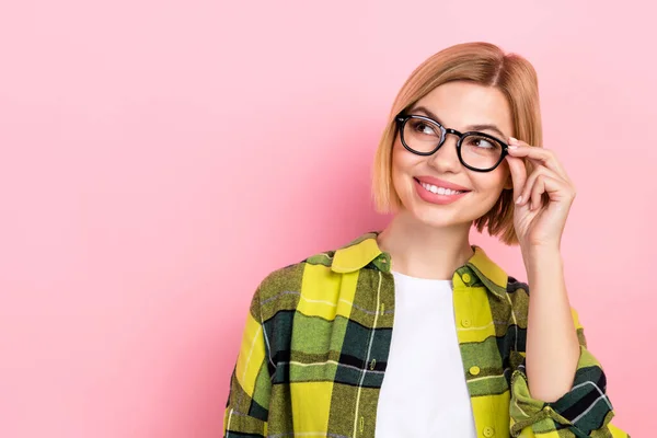 Photo of positive minded girl hand touch glasses beaming smile look empty space isolated on pink color background.