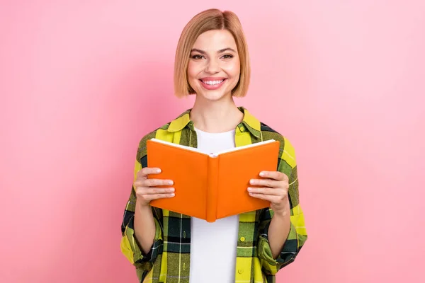 Portrait of intelligent positive lady toothy smile hands hold opened book isolated on pink color background.