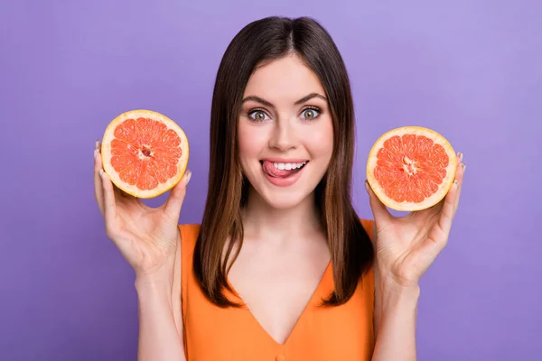 漂亮而兴奋的女士手拿着柚子片的肖像 舌舔齿在紫色背景下隔绝 — 图库照片