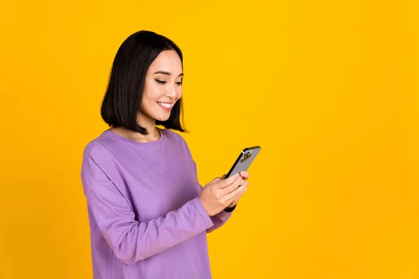 소녀가 보라색 셔츠를 스마트폰으로 대화하는 노란색 배경에 고립된 온라인 — 스톡 사진