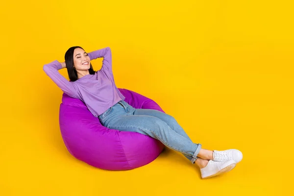 Full body photo of young satisfied korean girl hands head take nap no stress just chill soft bean bag isolated on yellow color background.